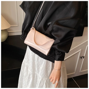 Glanzende lichtroze lakslederen mini-crossbodytas getoond op een model voor een hippe look