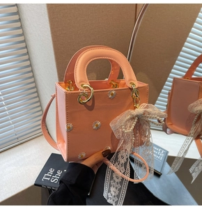 Detail of pink handbag with daisy embroidery and lace pearl bow accessory close-up