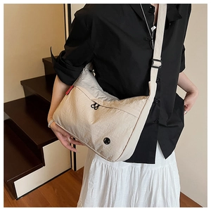 Detailed view of beige crinkled nylon messenger bag with black double zippers and wide strap