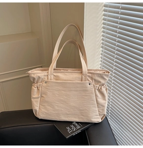 Détail d'un grand sac cabas beige avec poche frontale et cordons de serrage latéraux