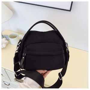 Detail of black nylon crossbody bag featuring silver hardware and wide adjustable strap