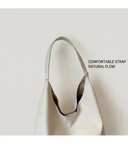 Detail of wide shoulder strap and V-shaped opening on a cream white oversized hobo bag