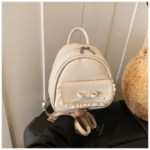 Detail eines beigen Mini-Lederrucksacks mit zartem Spitzenbesatz und süßem Schleifen-Akzent