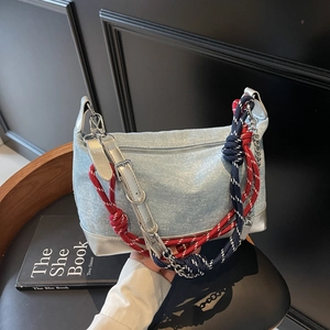 Close-up of light blue denim tote bag with silver leather base and rope handles