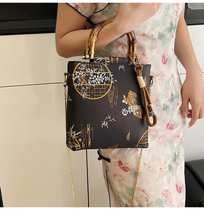 Detailed embroidery on black handbag with bamboo handle and traditional Chinese patterns