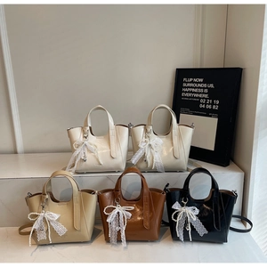 Minimalist tote bags in four colors with pearl lace charms on a marble display