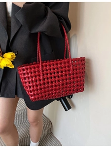 Red woven hollow beach tote bag with top handles shown in a lifestyle model shot