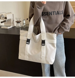 Detail of white canvas tote bag with functional black buckles and reinforced straps