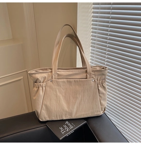 Gros plan d'un grand sac cabas beige avec rivets argentés et détails froncés latéraux