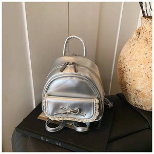 Nahaufnahme silberner Rucksack mit Schleife, Spitze und Metallic-Ledertextur