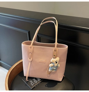 Rosa gewebte Tragetasche mit Bärenanhänger auf Ledersessel für einen edlen Look