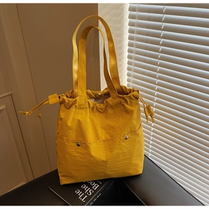 Close-up of bright yellow nylon tote bag with drawstring closure and two button pockets