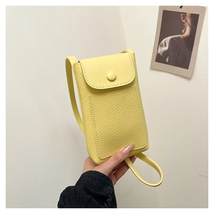 Detail view of a compact yellow pebble leather crossbody phone bag with flap button closure