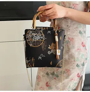 Detail of black silk handbag with orchid embroidery and natural bamboo handle