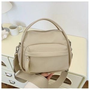 Detail of minimalist beige crossbody bag with wide shoulder strap and front zipper pocket