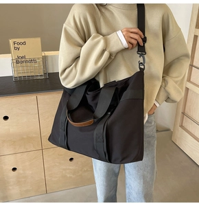 Detailed close-up of large black canvas tote bag with adjustable shoulder strap and hardware