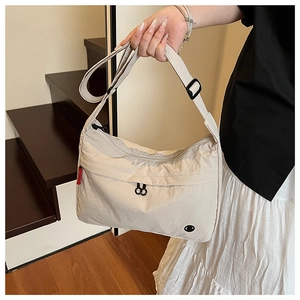 Detail of light beige nylon tote with adjustable black strap and red brand tag