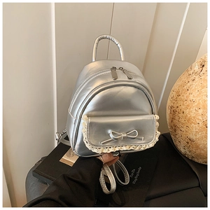 Detail eines silbernen Metallic-Minirucksacks mit Schleife, Spitze und Tragegriff