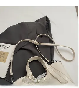 Detail of adjustable shoulder strap and pearl lace bow on cream bucket handbag