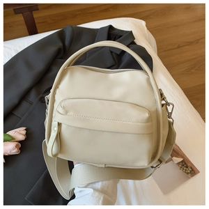 Detail of beige nylon crossbody bag with wide shoulder strap and front zipper pocket