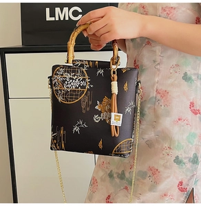 Detailed view of bamboo handle and floral embroidery on a black satin handbag