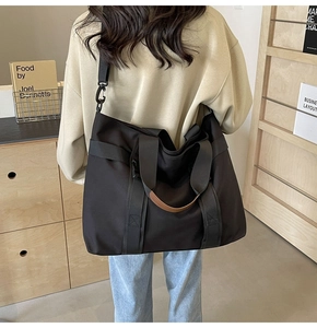Black canvas tote bag with brown leather handles and wide adjustable shoulder strap
