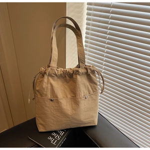 Detail of light khaki nylon bucket bag with drawstring closure and silver metal buckles