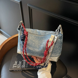 Detail of blue denim tote bag with silver trim and multi-strand braided straps