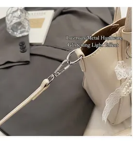 Detail of premium gold hardware buckle on a cream faux leather shoulder bag with lace