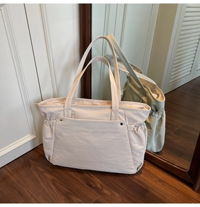 Vue détaillée du sac cabas en nylon crème avec poches latérales et rivets en métal