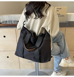 Detail of large black canvas tote bag with brown handles and wide shoulder strap for travel