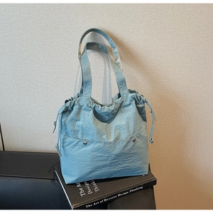 Detailed view of Morandi blue drawstring tote bag with textured nylon and silver metal studs