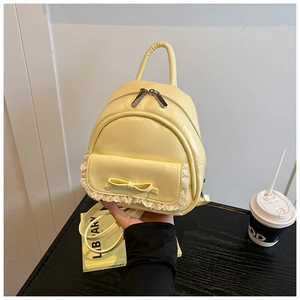 Nahaufnahme eines gelben Mini-Rucksacks mit weißer Spitze und schickem Schleifendetail