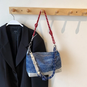Detail of denim tote bag with red blue white braided rope strap and silver bottom panel