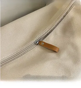 Detailed close-up of smooth metal zipper and brown leather pull on canvas shoulder bag