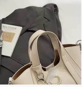 Detailed view of cream PU leather bucket bag with pearl chain and elegant lace accents