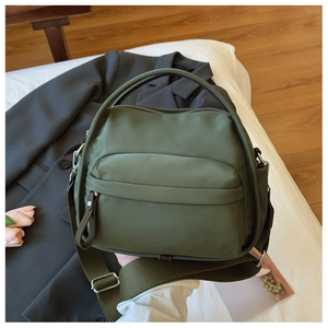 Detail of dark green nylon crossbody bag showing the waterproof texture and zip closure