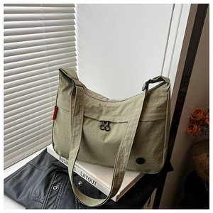 Detailed shot of an avocado green nylon crescent bag with wide strap and red side label