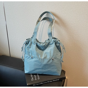 Close-up of light blue nylon tote bag with drawstring details and front metal buttons