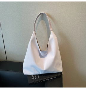 Detailed view of white hobo shoulder bag with vertical texture resting on a book