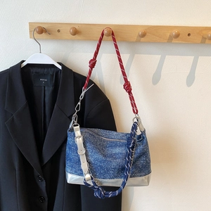 Detail of blue denim tote bag with red and white rope strap and silver metallic base