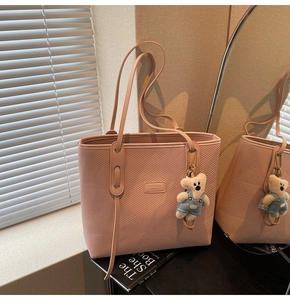 Detail der rosa gewebten Ledertasche mit Markenlogo und süßem Plüschbär-Anhänger