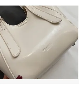 Close-up of soft cream leather texture with embossed fashion lettering on a bucket bag