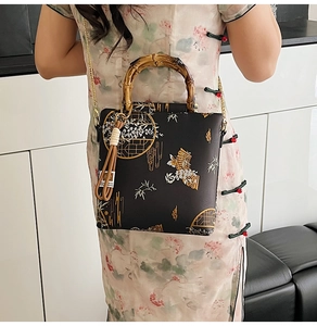 Detail of hand-held embroidered lace bag with bamboo handle and gold chain strap
