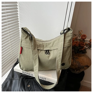Detail of light olive nylon crossbody bag with textured fabric and front zipper pocket