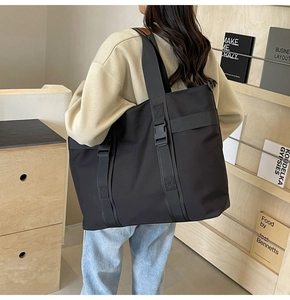 Detail showing the thick buckle and adjustable strap on a large black canvas tote bag
