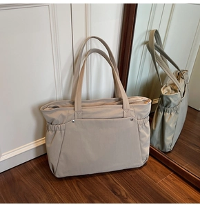 Gros plan d'un grand sac cabas beige en toile avec poches latérales et détails coulissants