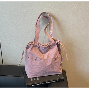 Detail of dusty rose bucket bag featuring drawstring closure and textured fabric
