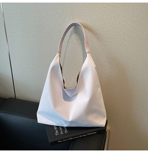 Detail shot of light pink textured hobo bag placed on black books for daily commute