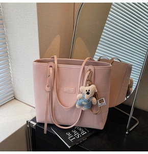 Detail der rosa gewebten Tragetasche mit Ledergriffen und süßem Plüschbär-Anhänger